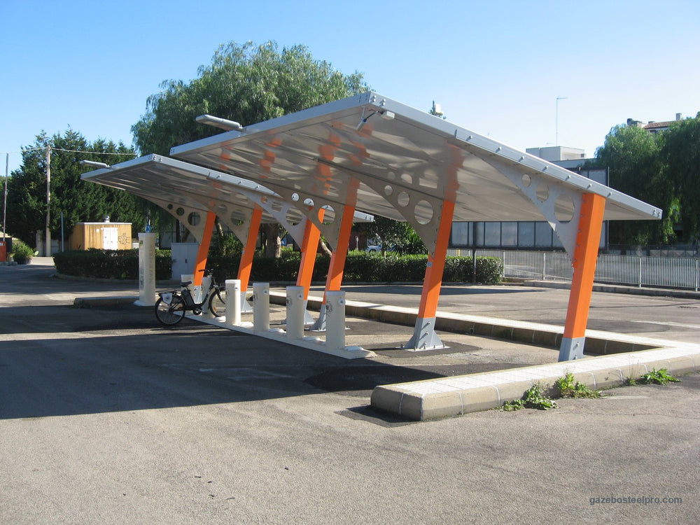 Carport Sunshine con piantoni scatolati arancioni e rinforzi in lamiera forata in un parcheggio, senza pannelli