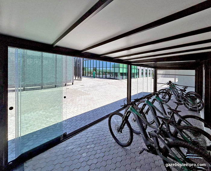 Dentro la pergola QBox Linea nera chiusa con vetrate scorrevoli: copertura bianca, traverse nere e biciclette