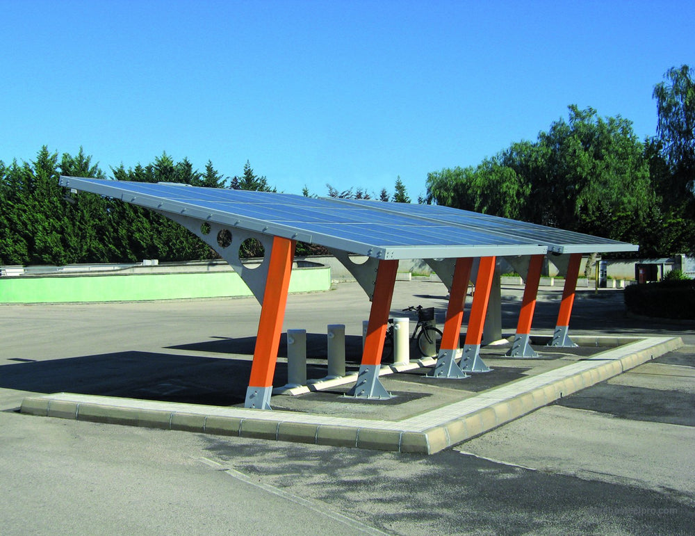 Carport Sunshine con piantoni scatolati arancioni e pannelli fotovoltaici sul tetto, più moduli in fila in un parcheggio